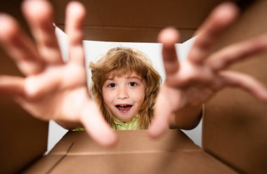 Çocuk karton kutunun içine bakıyor, alt manzara. Satın aldıklarınızı teslim ediyorum. Çocuklar doğum gününü kutlar. Doğum günü hediyesi. Kutusu açık çocuk hediyesini al.