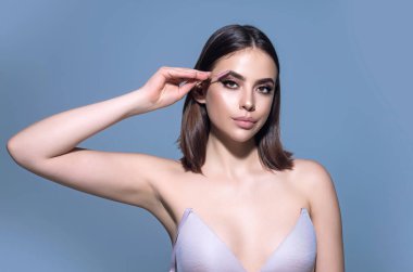 Woman shaping brown eyebrows. Woman eye with beautiful eyebrows. Shaped brows, long eyelashes. Paint eyebrows. Girl contouring eyebrows on isolated studio background