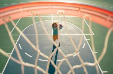 Çocuk basketbol oynamaya hazırlanıyor, dışarıda oyun alanında.