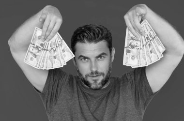 İzole edilmiş sarı arka planda dolar banknotlar halinde nakit para tutan adam. Bir sürü banknotla birlikte iş adamının stüdyo portresi. Dolar parası konsepti. Kariyer zenginliği işi. Nakit Dolar