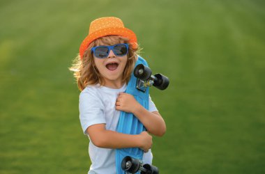 Kaykaylı çocuk. Çocuk kaykay tahtası. Yazın okul çocukları için sağlıklı bir spor ve aktivite. Spor eğlencesi. Uzun tahta, kaykay, peni tahtası konsepti