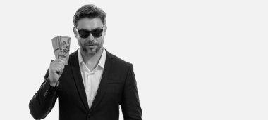 Üzerinde nakit para banknotları olan tişörtlü bir iş adamı sarı stüdyo geçmişinden izole edilmiş. 100 dolarlık banknot, finansal konsept.