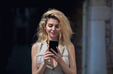 Portrait of blonde woman with mobile phone. Pretty girl talk by mobile cell phone. Call on phone outdoor. Millennial lady talk phone outsite in city. Woman hold mobile cellphone, chatting phones clipart