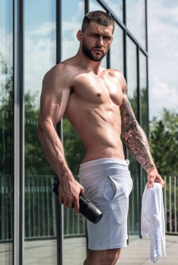 Egzersizden sonra güçlü bir genç adam. Spor kulübündeki erkek sporcu. Genç adamın fitness antrenmanı var. Teras yakınında poz veren erkek sporcu. İnsanlar spor ve sağlıklı yaşam tarzı konsepti
