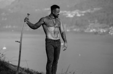 Çiftçi adam tırpan kullanıyor. Alps Gölü yakınlarındaki yeşil çimen tarlasında tırpanlı bir çiftçi. Adam çim biçmiş. Kır çiftçisi yaz çayırında geleneksel tırpanla çim biçiyor.