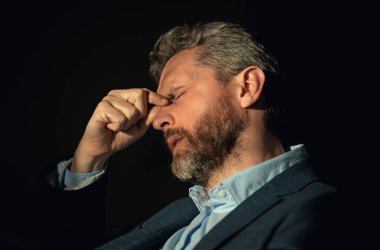 Yorgun adamın korkunç bir baş ağrısı var. Bitkin, sağlıksız hisseden, baş ağrısı hastalığına üzülen bir adam. Stresli orta yaşlı bir adamın baş ağrısı olan portresi. Migren ve baş ağrısı konsepti