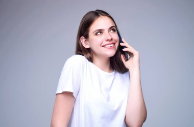 Stüdyonun arka planında izole edilmiş telefon aygıtı uygulaması kullanan bir kız. Akıllı telefon tutan, cep telefonuyla konuşan bir kadın. Telefon kullanan bir kız, stüdyo resmi. Kadın telefonla konuşuyor.