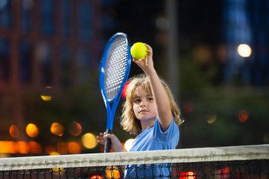 Sahada tenis oynayan küçük çocuk.