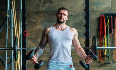 Muscular man lifting weights at gym. Handsome guy prepare to do exercises with dumbbell
