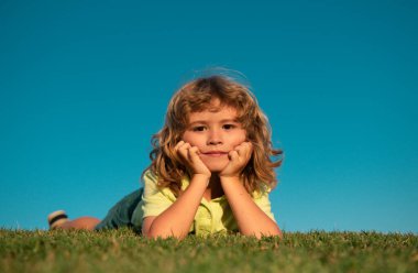 Yazlık parktaki çimlerin üzerinde oynayan mutlu çocukların portreleri. Komik çocuk yüzü dışarıda.
