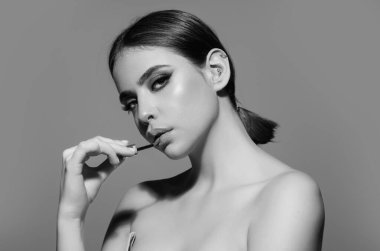 Studio portrait of beautiful woman with red lipstick. Beautiful young woman applying lipstick on her lips, isolated on studio background