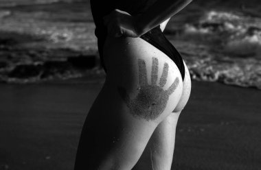 Summer beach concept. Sandy woman buttocks on the beach. Sexy summer woman body. Sand hand print on butt. Vacation at Paradise. Ocean beach relax, travel