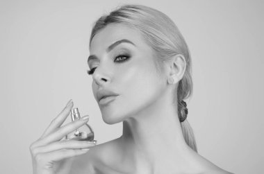 Parfüm kullanan güzel romantik bir kız. Parfüm şişesi olan kadın. Kadın parfümleri sunar. Parfüm şişesi, sprey aroma. Kadın parfüm şişesi tutuyor.