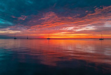 Gökyüzünde gün batımı ve renkli bulutlar. Güneşin doğuşuyla sakin deniz