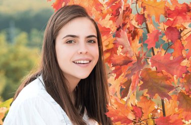 Sonbahar mevsimi. Yaprakları yapraklı genç bir kadının portresi. Sonbaharda güzel bir kız. Sonbaharda sarı yapraklı şehvetli bir kadın. Sonbahar arkaplanında yaprağı olan güzel bir kadın.