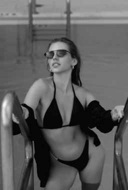 Yüzme havuzunda bikinili genç bir kadın, havuz başında seksi bir poz. Yaz tatili. Otelde havuz başında bikini mayo giymiş bronzlaşmış bir kız. Yaz turizmi