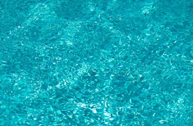 Yüzme havuzundaki mavi suyun arka planında güneş yansıması, havuzda dalgalı su dalgaları. Temiz su arkaplanı