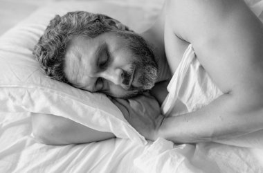 Yatağa git. Yaklaş. Erkek model beyaz yatakta uyuyor. Seksi üstsüz adam yatak odasında uyuyor. Latin kökenli olgun bir adam sabahları evde uyuyor. İyi uykular, uyku vakti. Yatakta uyuyan adam.