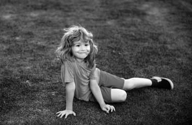 Parktaki çimlerin üzerinde yatan küçük mutlu çocuk.