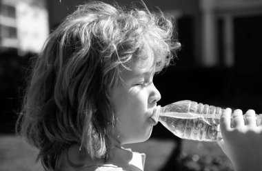 Şişeden su içen sevimli bir çocuğun portresi. Kafkas çocuk yüzünü kapatın. Komik çocuğun yakın plan kafası.