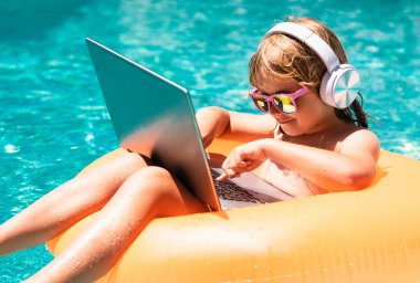 Çocuk havuzda dizüstü bilgisayarla çalışıyor. İş seyahati