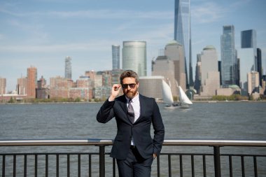 New York 'ta zengin bir işletme yöneticisi duruyor. İş dünyası Amerikan başarısı. Amerikan iş rüyası. Manhattan yakınlarında takım elbiseli Amerikalı işadamları. ABD 'de başarılı bir iş