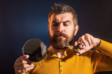 Berber makası ve ayna, berber dükkanı. Berber makasıyla bıyık ve sakal kesmek. Reklamcılık ve berber dükkanı konsepti. Sakallı adam portresi. Berber ve berber dükkanı konsepti