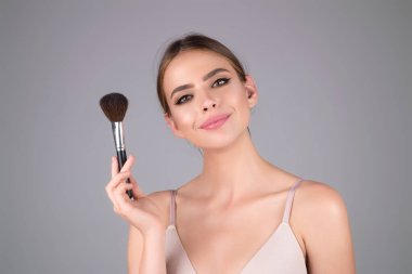 Beautiful woman applying make-up powder on the cheek. Cosmetic powder brush. Perfect skin and natural makeup