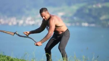 Man cut grass. Rural farmer mowing grass with classic traditional scythe. Rural farmer on summer meadow mowing grass. Summer farm. Farmer making hay. Farmers lifestyle in natural environment