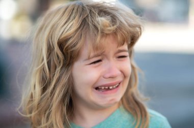 Ağlayan bir çocuğun portresi. Ağlayan bir çocuk. Acı içinde ağlayan bir duygu. Yanağına gözyaşı damlıyor.