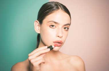 Attractive young woman applying lipstick. Lips Protection. Nice girl with beautiful face. Portrait of female model with natural makeup. Moisturizing lip balm. Healthy beauty