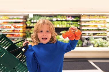Taze domates sebzeli çocuk. Çocuk dükkandan taze sebze ve meyve seçiyor. Çocuk marketten yiyecek alıyor. Marketten satın almak. Süpermarketten aldıklarım.