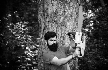 Sakallı yakışıklı bir genç adam ağaç taşıyor. Ormanların tahrip edilmesi doğal ekosistemlerin bozulması ve istikrarsızlaşmasının başlıca nedenlerinden biridir.