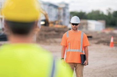 Kasklı iki inşaat işçisi dışarıda çalışıyor. İnşaat işçileri inşaat alanında çalışıyor. İnşaat işçisi olmak çok fazla fiziksel güç gerektirir.