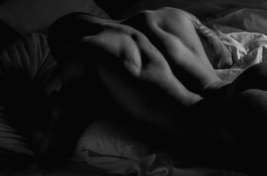 Man lying on bed. Sexy guy in bedroom. Young handsome man in bedroom. Shirtless sexy male model lying on bed in his bedroom. Body portrait of a nude male model in bed