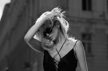 Sokakta yürüyen güzel sarışın kızın portresi. Moda kıyafetleri içinde genç bir hippi kadın. Moda sokağı. Sokakta poz veren kaygısız seksi kadın. Güneş gözlüklü sarışın kadın. Sokak tarzı