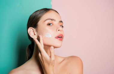 El kremi sürerek yanağa dokunan güzel genç bayanın portresi. Kişisel bakım rutini ve sağlıklı ruh hali. Saf pürüzsüz cilt ve doğal güzellik kavramı