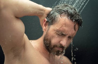 Orta yaşlı bir adam banyoda saç yıkıyor. Küvette banyo yapan adam. Yüzü duşta köpüklü. Banyo yapan adam duş alıyor. Duş alan adamı kapatın. Duş konsepti. İnsan duşta su altındadır.