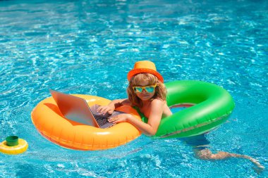 Yaz işi. Uzaktan kumandalı çocuk bilardoda çalışıyor. Küçük iş adamı yazın havuz suyunda dizüstü bilgisayarda çalışıyor.