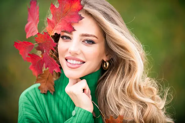 Young woman in autumn park. Warm sunny weather. Fall concept. Hello autumn. Happy woman with autumn yellow leaves outside. Beautiful autumn fall time in nature