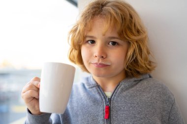 Kid holding a glass of fresh milk. Child with milk moustache drinking milk. Healthy breakfast for children. Healthy eating concept for kids. Little kid boy hold cup of milk