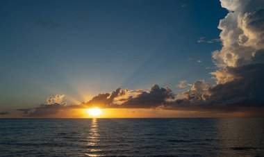 Dramatik gün batımı gökyüzü. Deniz. Bulutların arasından gün batımını izleyen sakin bir deniz. Günbatımı okyanusu ve gökyüzü arka planı. Huzurlu deniz manzarası. Günbatımı deniz suyunun üzerinde bir ufuk. Güneşin doğuşuyla sakin deniz