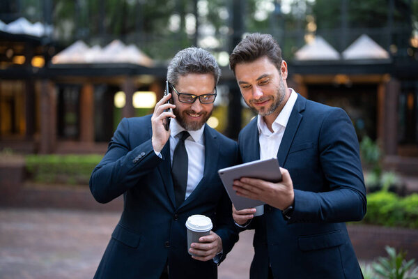 The two business team worked together to achieve their goals. Business men team using tablet laptop outdoor. Businessmen looking tablet with their business success in city background