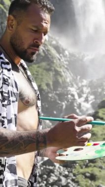 Artist hipster man drawing outdoor. Painting art. Man artist draw pictures in alps mountain. Man painting with brushes oil or acrylic paint. Male artist paints a picture on canvas