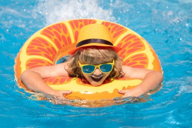 Yüzme havuzunda şişme yüzük takan çocuk. Çocuklar turuncu yüzgeçle yüzerler. Su oyuncağı, çocuklar için sağlıklı açık hava sporları. Çocuklar plaj eğlencesi