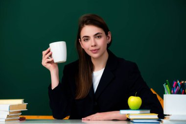 Sınıfta çay içen fincanlı öğrenci. Üniversitede kahve molası. Genç üniversite öğrencisi tahtanın yanında çalışıyor. Eğitim konsepti. Lisede ders ve ödev