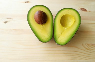 Avokado meyvesi. Çiğ meyveler sağlıklı yeşil yiyecekler. Yarım avokado. Ahşap zemin üzerinde avokado