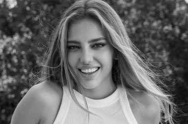 Mutlu genç bayan kameraya bakıyor ve gülümsüyor. Güzel gülümseyen genç bayan. Güzel kız gülümseyerek gülümsüyor. Mutlu ve gülümseyen kadın yüzü. Otantik mutlu kadın portresi