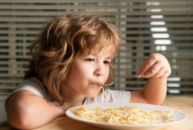Makarna ve spagetti yiyen küçük sarışın bir çocuğun portresi. Komik çocuk suratı