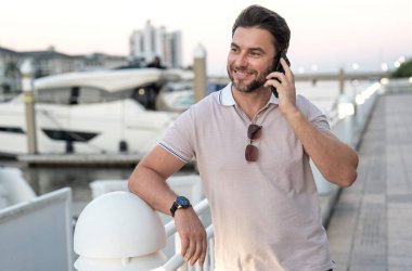 Şehirde telefonla konuşan yakışıklı, kendine güvenen bir adamın portresi. American City 'de telefonla konuşan adam. Polo giymiş seksi bir adam. Moda erkeği Tampa 'da sokakta poz veriyor. Bisiness telefon görüşmesi